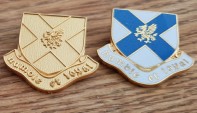 Round enameled metal badge with shield on the front